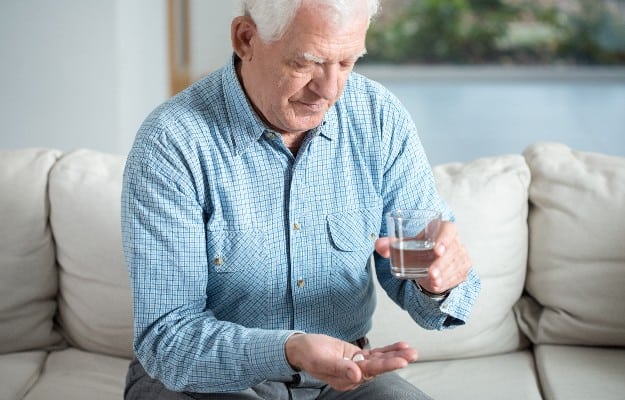 senior man taking pill and drinking water | The Pain of Pills for Seniors! And the Simple Cure to Managing Medications