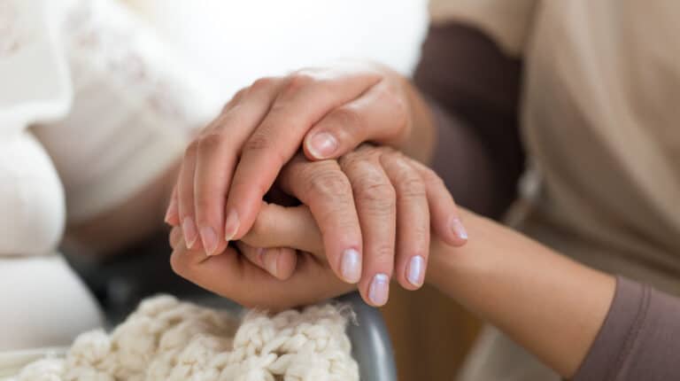 caregiver-and-senior-woman-holding-hands | 4 Surefire Ways for How To Deal With Caregiver Guilt And Other Caregiving Emotions