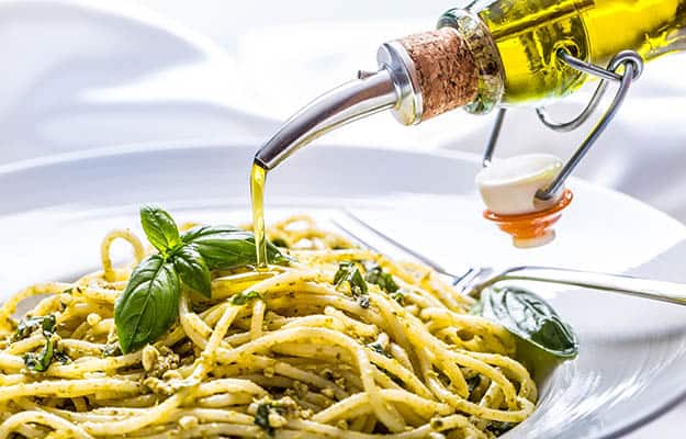 Spaghetti with homemade pesto sauce pouring olive oil and basil leaves | 9 Hearty And Healthy Dinner Recipes Your Senior Parents Will Love