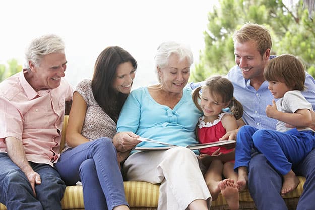 Multi-Generation-Family-Reading-Book-On-Garden-Seat | Why Social Interactions Are Important To Keep Your Parents Healthy
