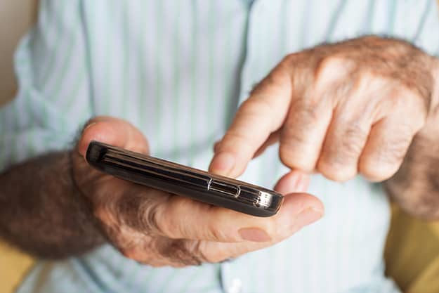 closeup-of-an-old-caucasian-man-uses-a-smartphone | 5 Engaging Social Media Platforms Seniors Will Enjoy
