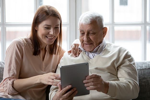 father-digital-tablet-user-asking-adult-daughter-for-help | 5 Engaging Social Media Platforms Seniors Will Enjoy