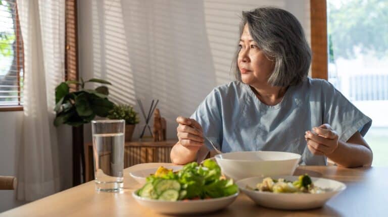 elder woman eating alone and looking out the window | 4 Common Senior Eating Problems and How to Combat Them