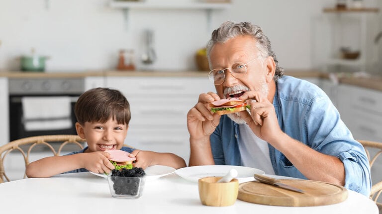 12Oaks-Little boy with his grandfather eating tasty sandwiches at table in kitchen-as-6 Quick _ Easy to Prepare Finger Food Ideas for Seniors-Feature
