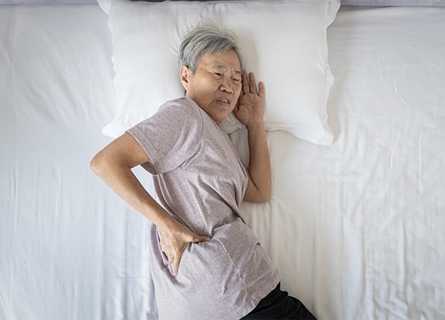 12Oaks-Asian senior woman suffering from back ache sore waist while sleeping-ss-Worst Sleep Positions to Avoid