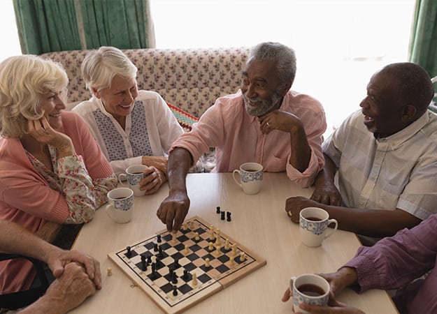 12Oaks-High angle view of group of senior people playing chess on table in living room at nursing home-ss-7 Strategies to Support Seniors_ Brain Health