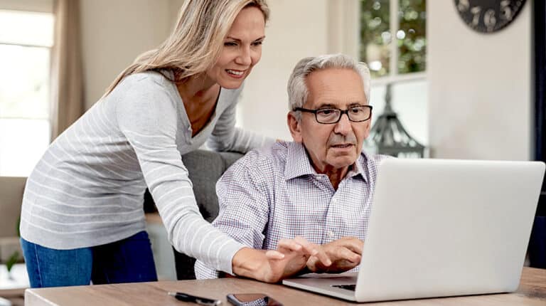 12oaks-Senior man and mature daughter smiling and looking at laptop at home-ss-Easy Ways to Teach Seniors Proper Use of Computer-Feature