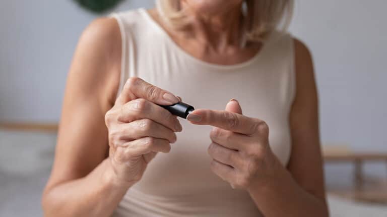 Diabetic-mature-woman-hold-use-blood-glucose-meter-in-bedroom---Proper-Ways-on-How-to-Manage-Diabetes-in-Seniors---ss-feat