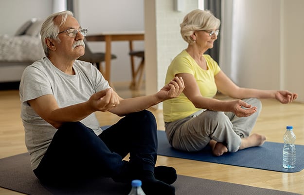 Senior-man-and-his-wife-practicing-Yoga-while-working-out-together-at-home---Practice-Stress-Reducing-Techniques---ss-body