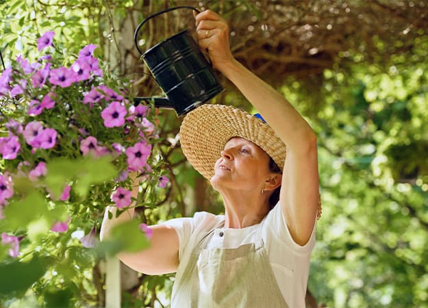 12Oaks-Senior woman waters the flowers in a hanging pot-ss-3. Gardening Decreases the Risk of Stroke