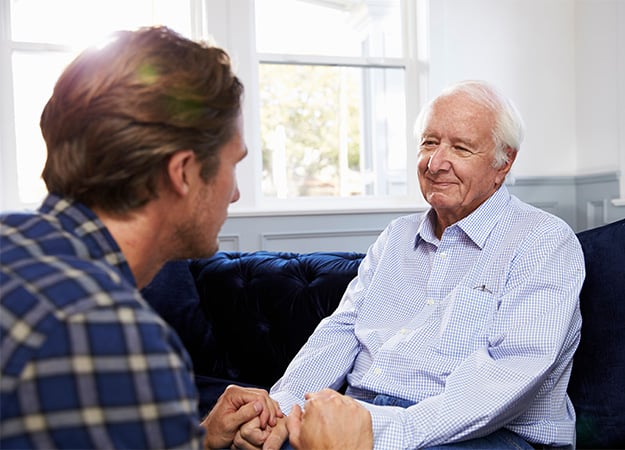 12Oaks-Adult Son Talking To Depressed Father At Home-as-How to Support Grieving Parents