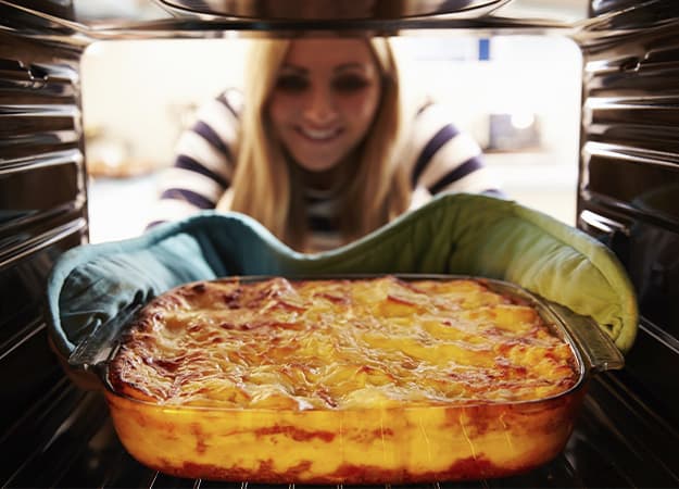 12Oaks-Woman Taking Cooked Dish Of Lasagne Out Of The Oven-as-Lasagna