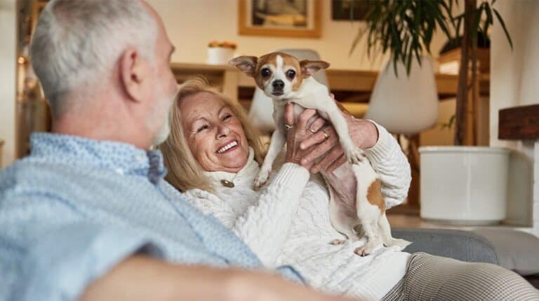 12Oaks-Happy retired couple with pet dog on sofa-ss-8 Best Dog Breeds That Are Great Companions for Seniors and Retirees-Feature