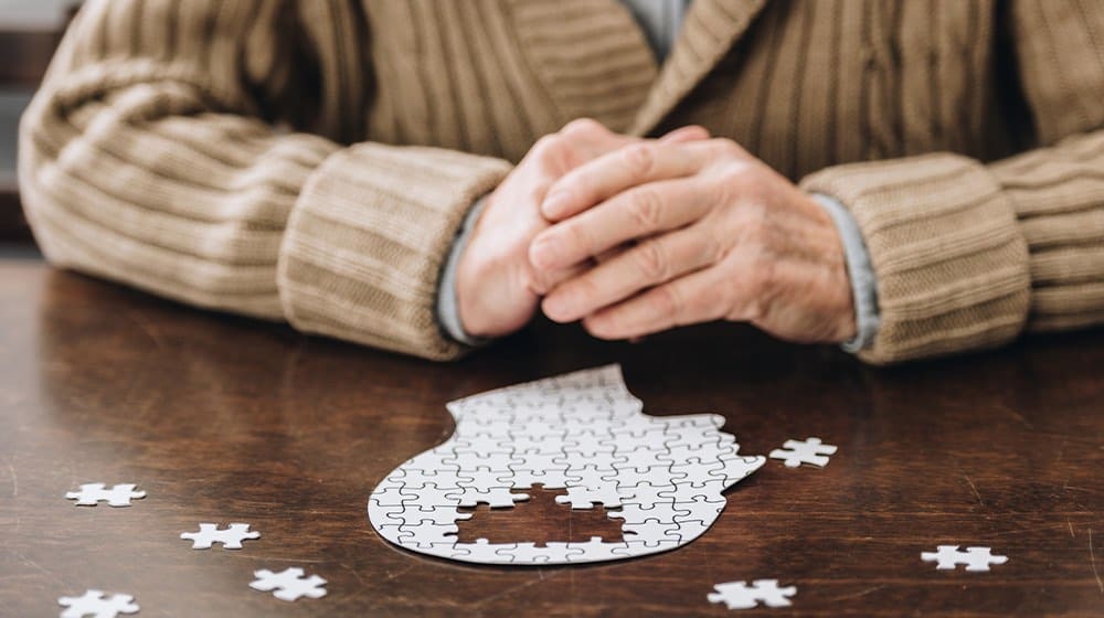 12Oaks-cropped view of senior man playing with puzzles on table-as-Aging and Mental Health _ Can Stress Cause Dementia_-Feature