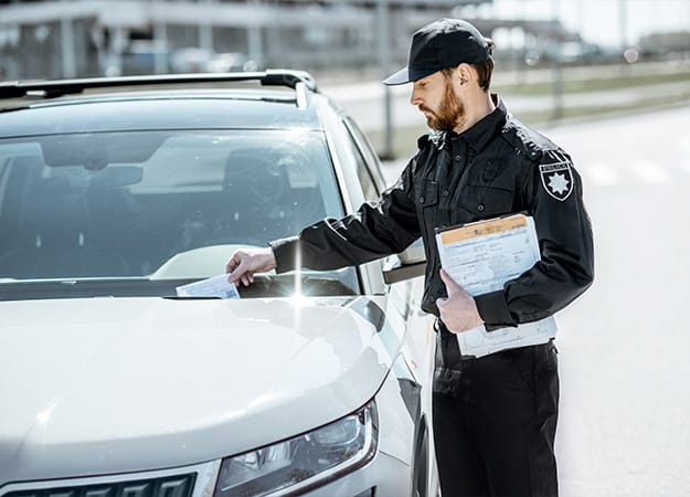 12Oaks-Policeman putting fine for improper parking on the windshield of the car on the roadside-as-6 They Receive More Traffic Tickets or Warnings