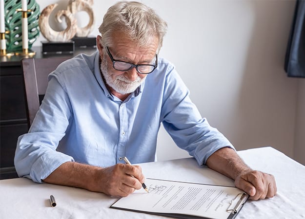 12Oaks-Senior old man elderly examining and signing document-as-A Step-by-Step Guide to Getting a Power of Attorney for Your Parent