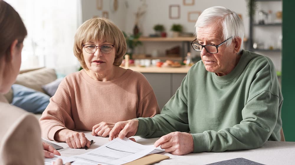 12Oaks-Senior couple consulting about financial documents with consultant they have a meeting at home-as-4 Elderly Care Documents You Need To Secure For Your Parents-Feature