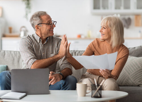 12Oaks-Mature Couple Holding Papers And Giving High-Five Reading Bills Indoors-as-Retirement Planning Checklists- Tips _ Steps to Consider
