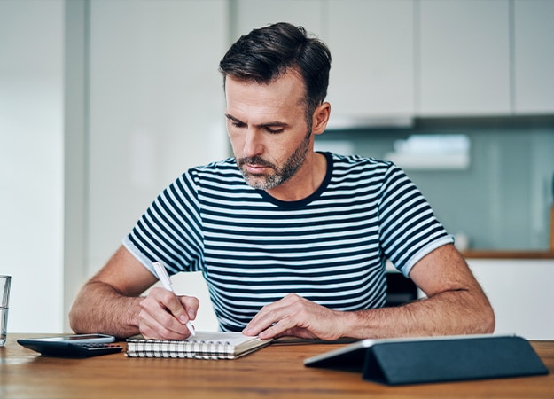 12Oaks-Thoughtful man writing in notebook while managing budget at home-as-3 Social Security Benefits