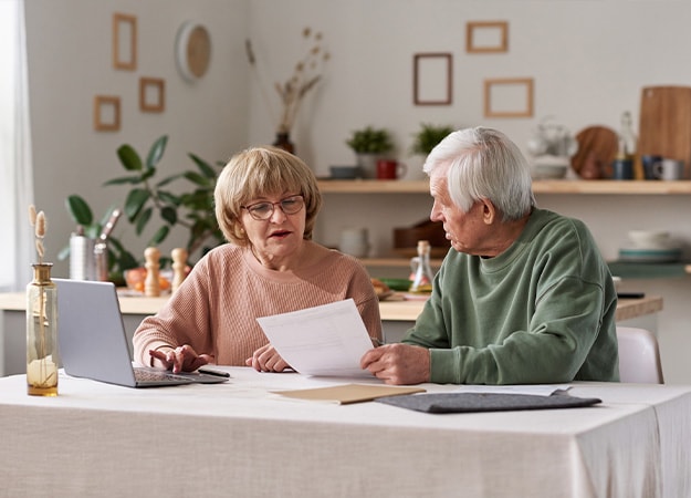 12Oaks-Senior couple sitting at the table with laptop and working with financial documents at home-as-What is Estate Planning_