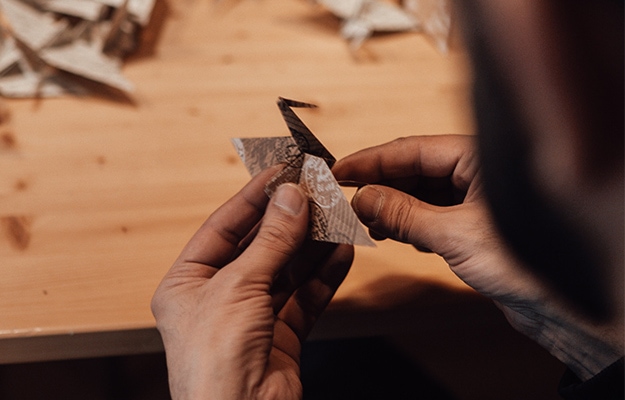 Faceless-man-making-origami-crane-from-paper-near-table---Spring-Craft-and-Creative-Arts-Activities---px-body