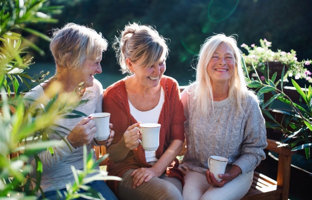 Senior-women-friends-with-coffee-sitting-outdoors---Outdoor-Spaces----ss_body