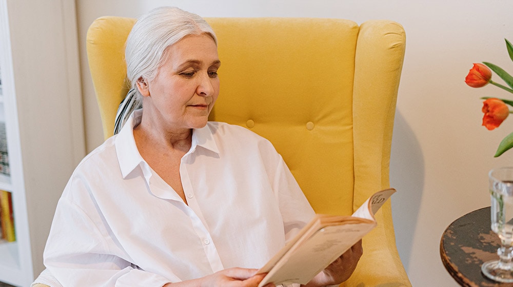 an-elderly-woman-sitting-on-a-couch-reading-a-book---6-Books-About-Retirement-Life6-Inspiring-Books-About-Retirement-and-Aging--px-feat