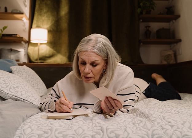 12Oaks-Elderly woman on the bed writing letter-pxls-1 Express Emotions Through a Hand-Written Letter