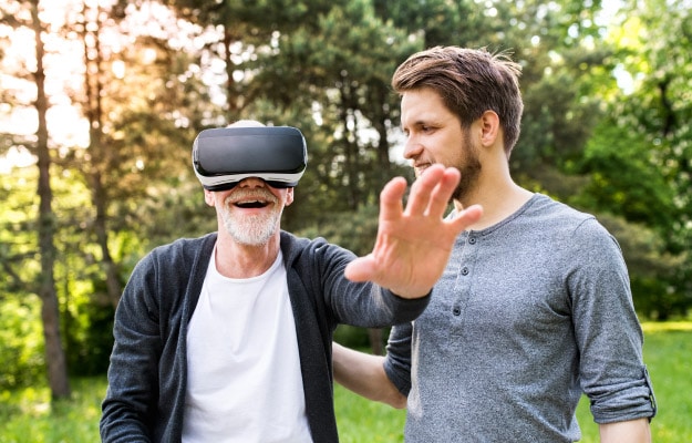 Young-man-and-his-senior-father-with-VR-glasses-outdoors-Virtual-Reality-How-Does-It-Benefit-Seniors
