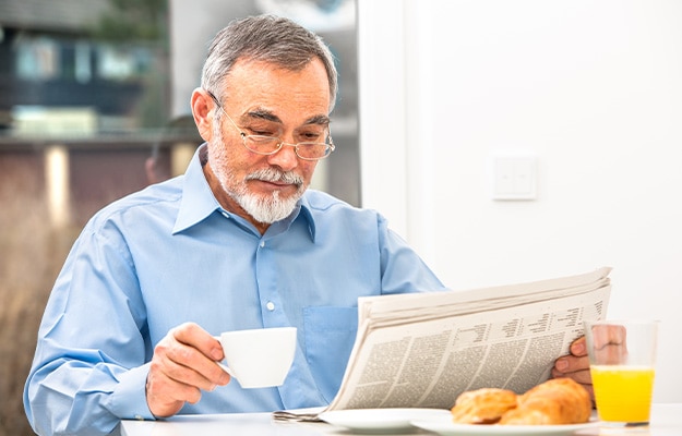 12Oaks-Senior-man-with-glasses-reading-newspaper-at-breakfast-ss-7-Limit-Caffeine