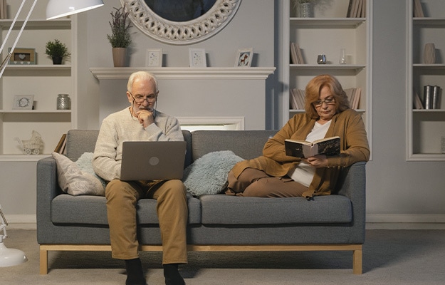 12Oaks-Elderly-couple-sitting-on-sofa-reading-books-pxls-1-Read-_-Research