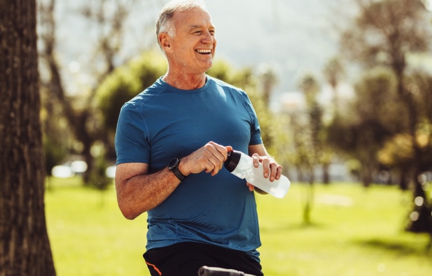 Senior-in-fitness-wear-drinking-water-sitting-on-bicycle-Hydration-Tips-for-Seniors_6-Drink-Water-During-Exercise