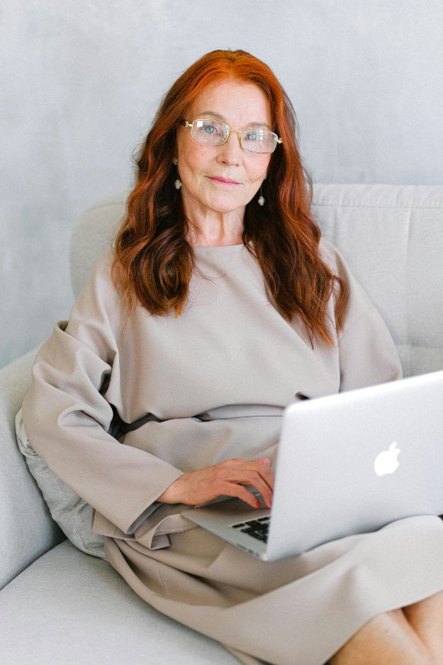 Charming elderly woman using laptop on sofa pexels