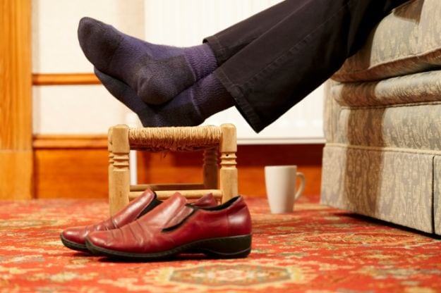 Feet resting on foot stool no shoes with cup of hot drink for relaxation by senior person