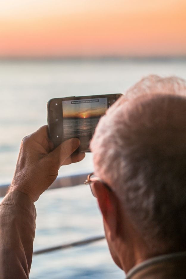 Anonymous male taking photo of ocean on smartphone at sunset pexels