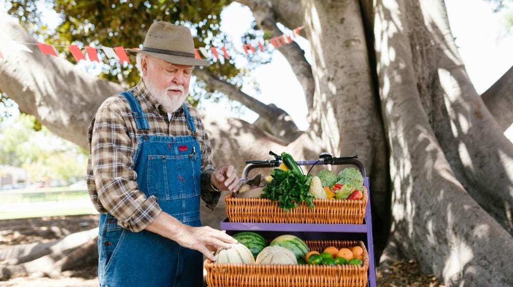 Farmer Standing by a Fruit Stand