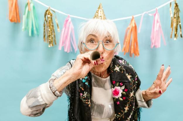 Elderly Woman Blowing a Party Horn | celebration of life ideas px