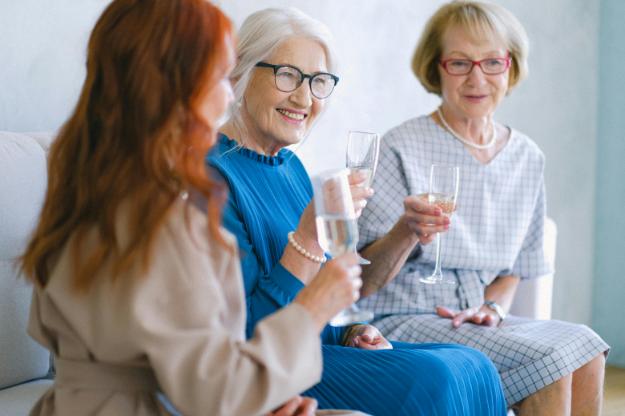 Senior positive women with glasses of champagne talking and smiling | celebration of life ideas px