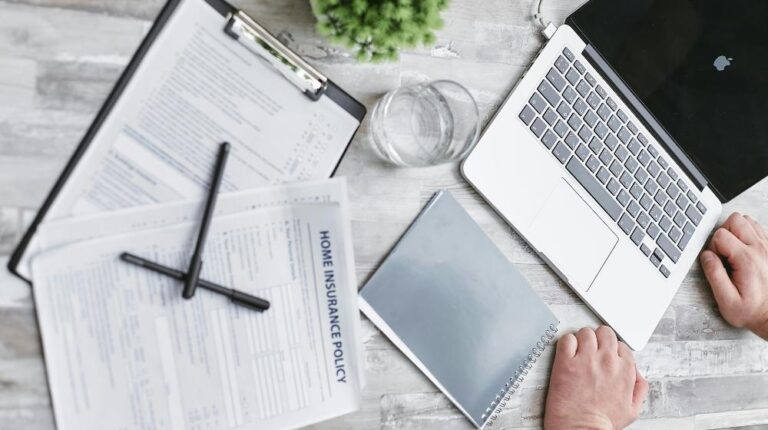 Person Writing on White Paper Beside Clear Glass Mug and Silver Macbook px featured image (1)